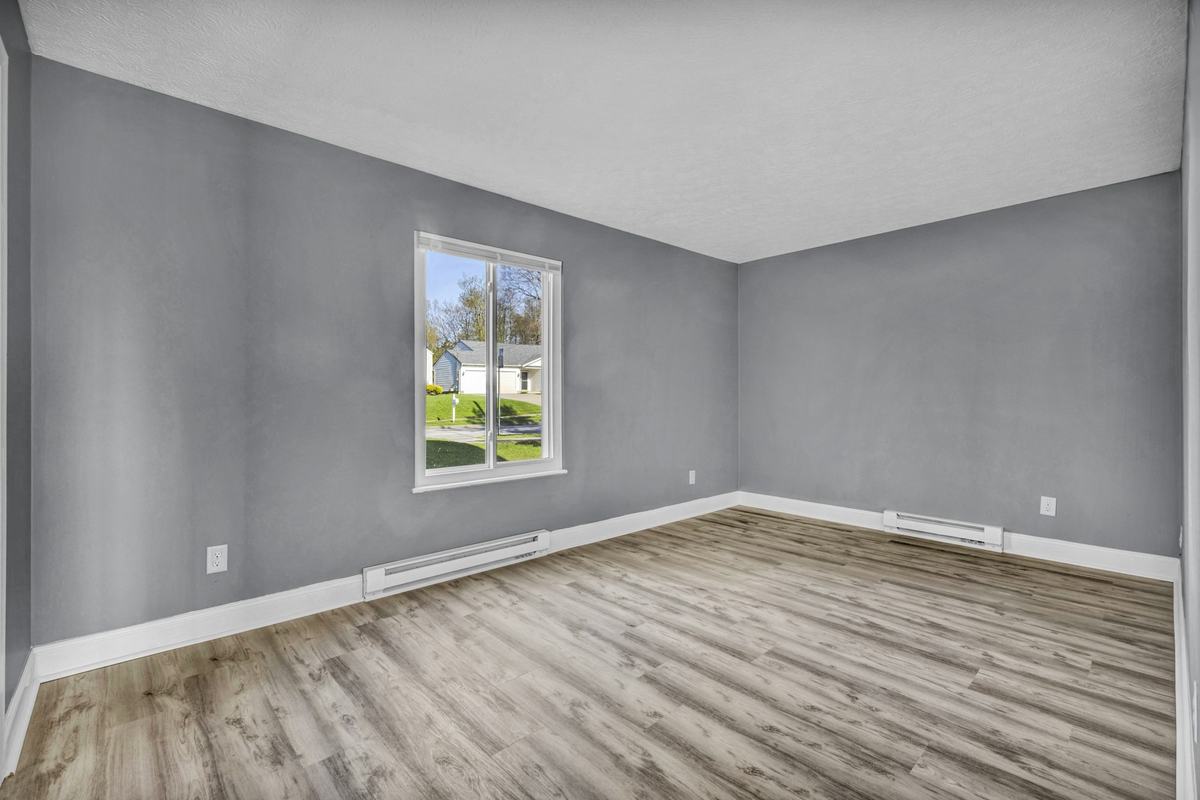 Empty room with gray walls, white baseboards and light wood-look flooring.