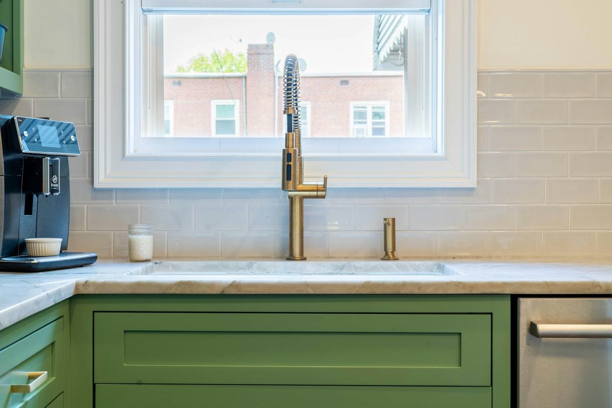 Green painted shaker-style base cabinet below a kitchen window and sink.