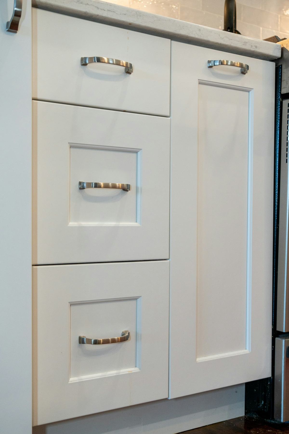 White cabinet drawer fronts and a door with metal pulls.