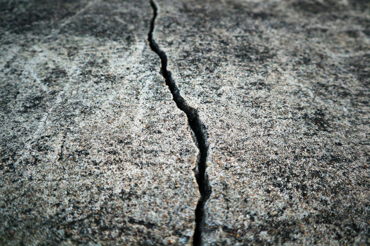 Close view of a crack opening through a concrete surface.