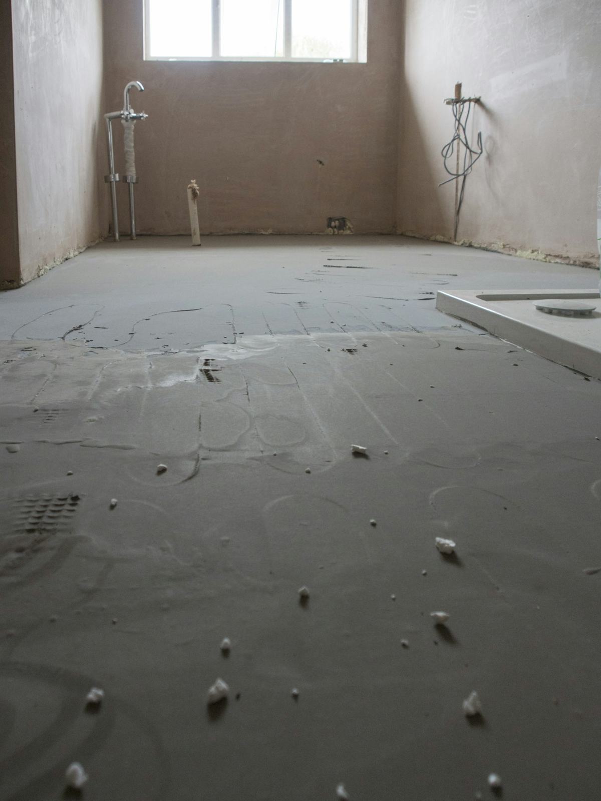 Freshly placed, smooth gray floor surface in a room under renovation.