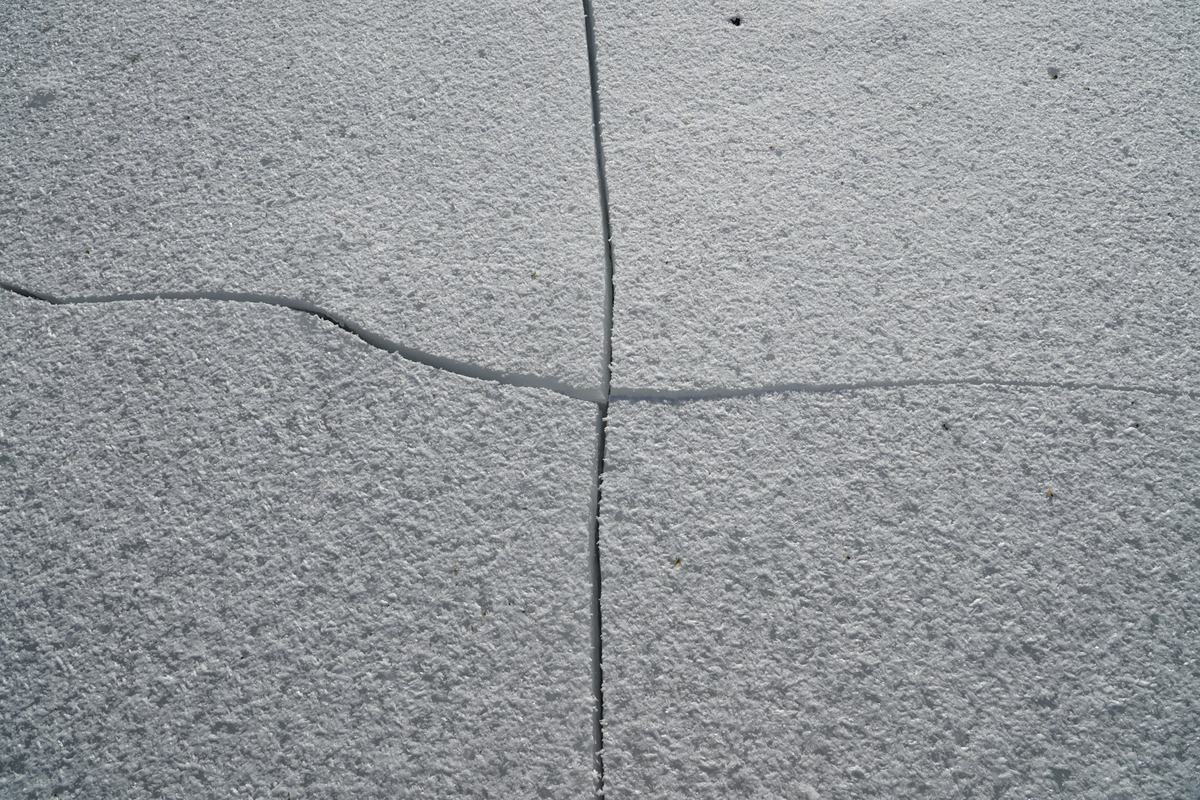 Hairline cracks crossing at right angles in a concrete surface.