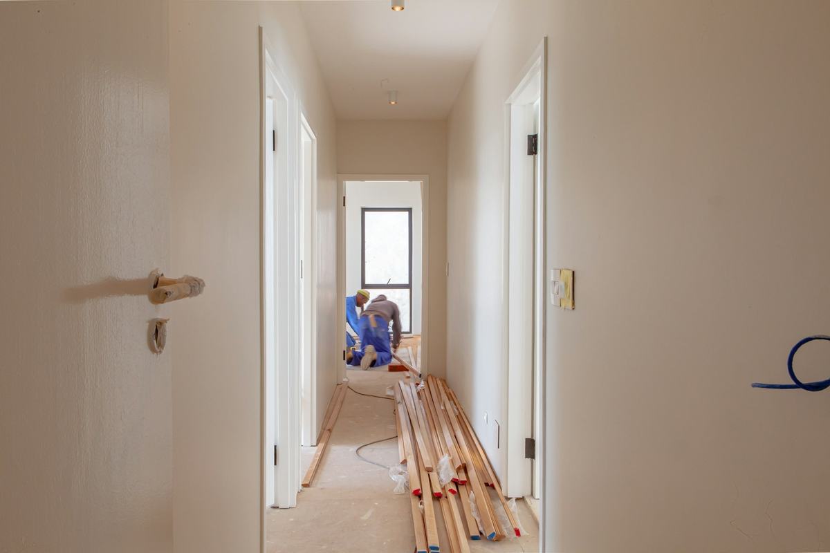 Hallway with newly hung interior doors and lengths of trim on the floor while work continues.