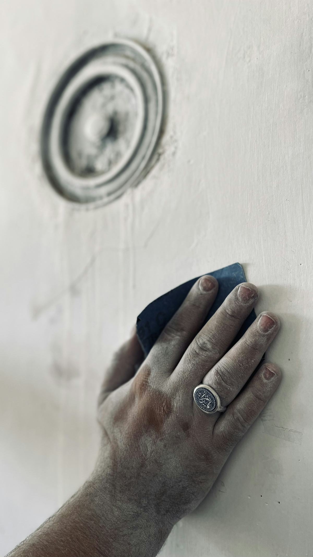 Hand sanding a white wall surface with a sanding sponge.