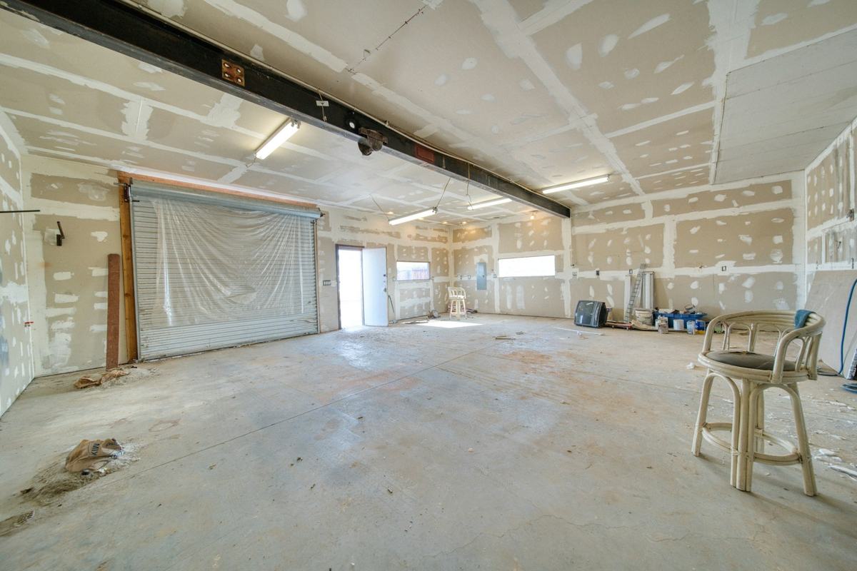 Large interior with drywall hung on walls and ceiling, joints taped and fasteners spotted with compound.