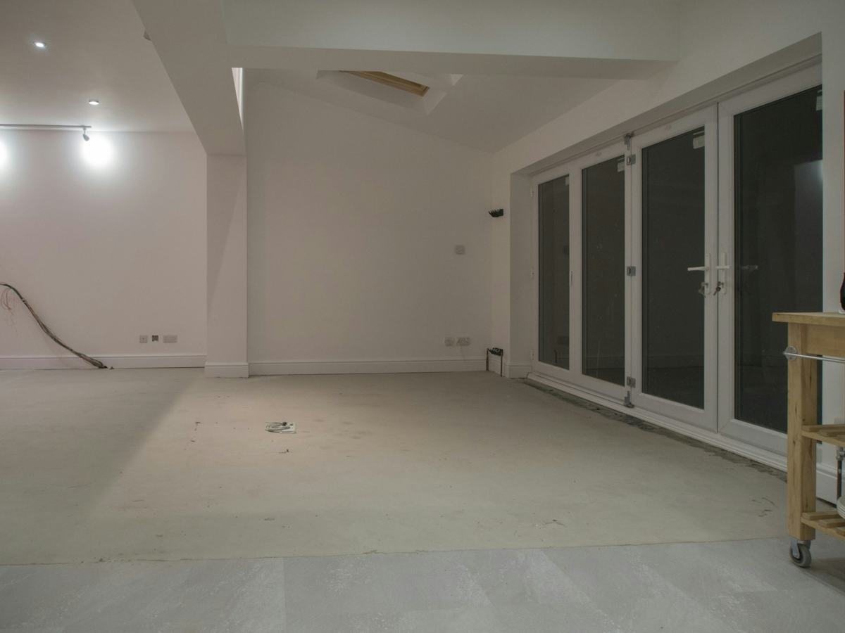 Empty room with white walls and a bare, cleared floor ready for new flooring.