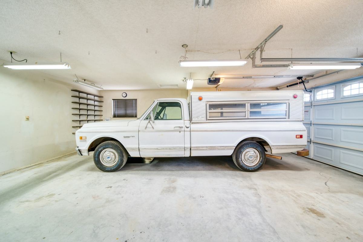 Residential garage with a bare, stained concrete floor and a pickup truck parked inside.