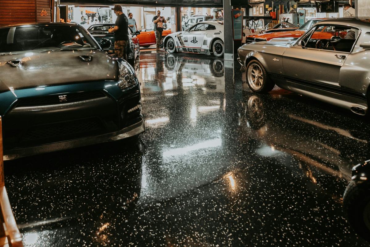 Dark, glossy speckled garage floor reflecting overhead lights, with vehicles parked on it.
