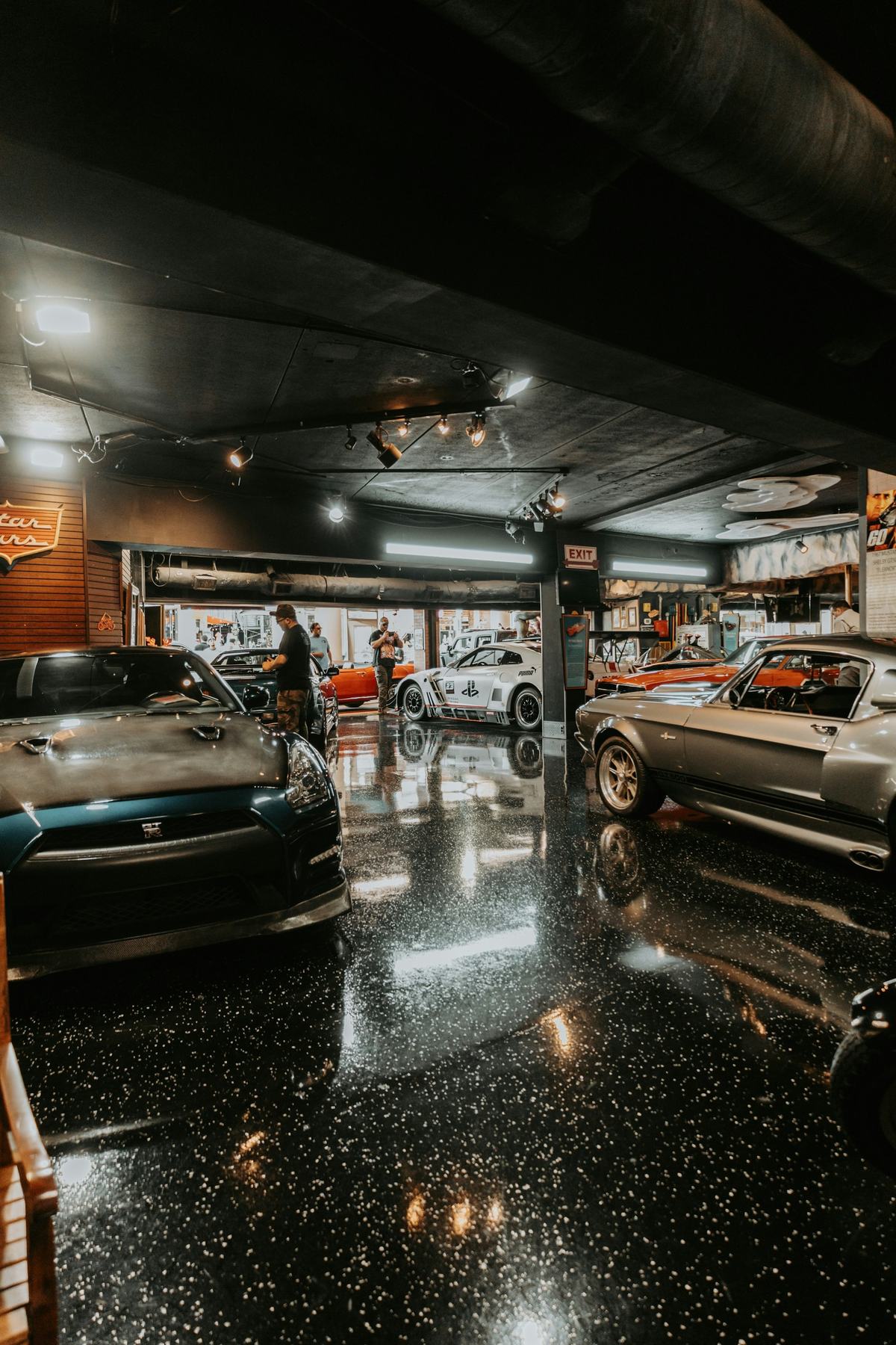 Dark, glossy speckled garage floor reflecting overhead lights, with vehicles parked on it.