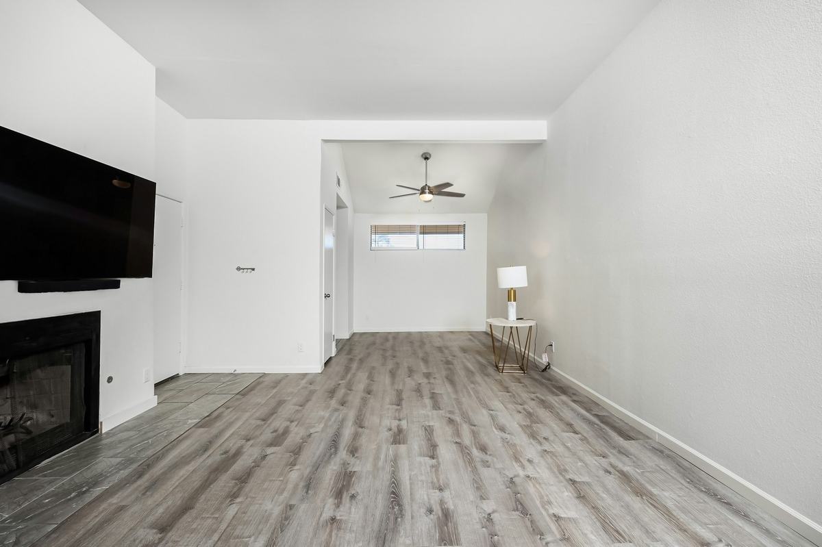 Long living room with white walls and gray wood-look plank flooring.