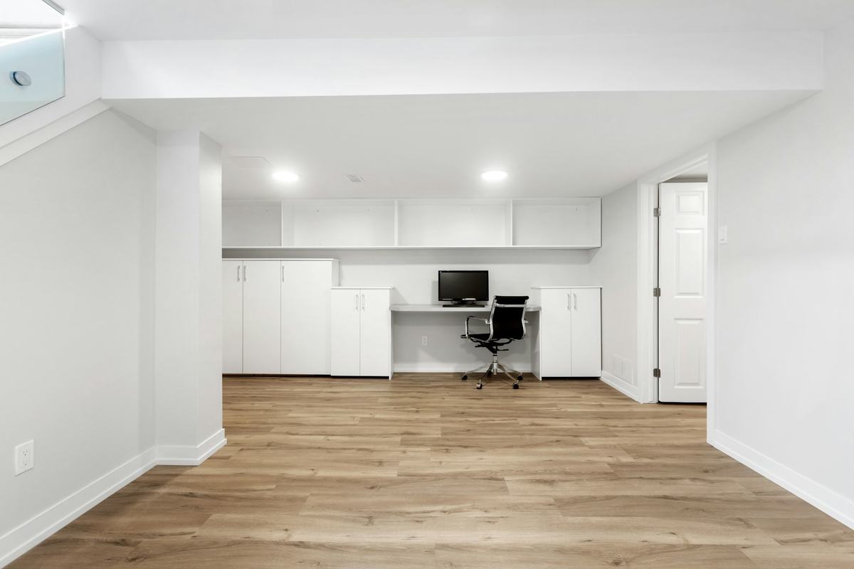 Open finished room with white walls, white baseboards and light wood-look plank flooring.