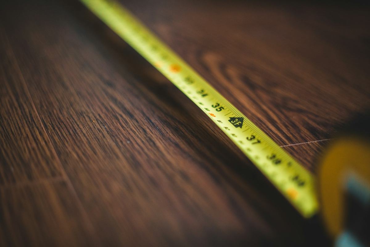 Tape measure extended across a dark wood-grain plank surface.