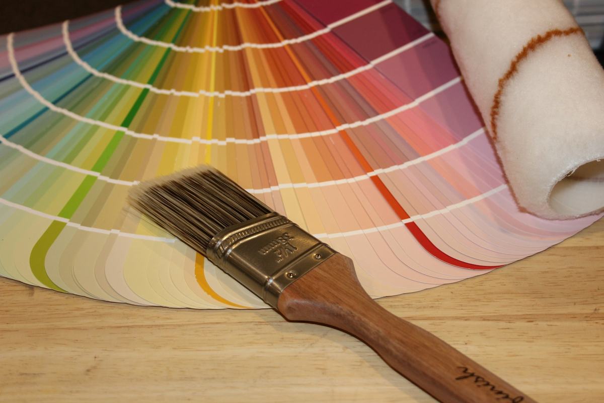 Paint color fan deck spread out beside a brush and roller cover.